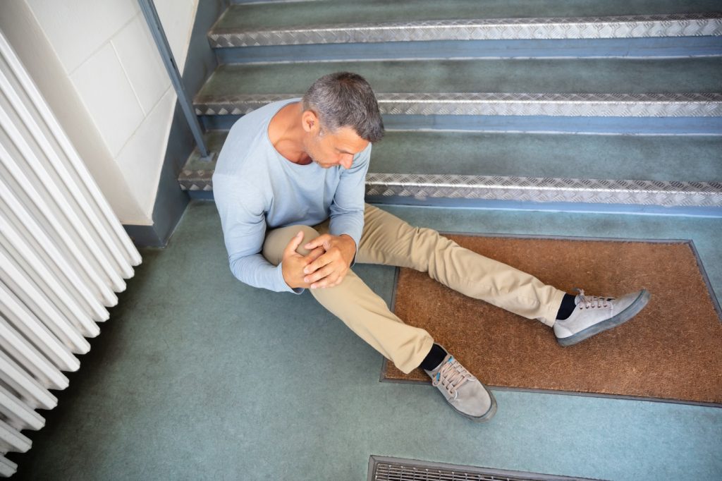 older man sitting at stairs after falling