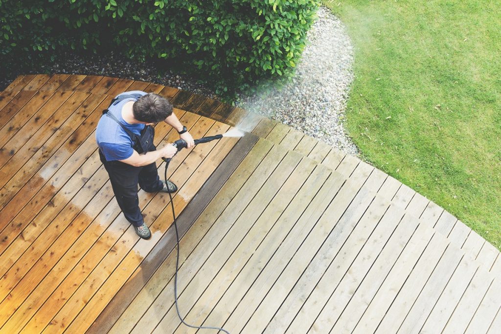 Man cleaning deck with power washer