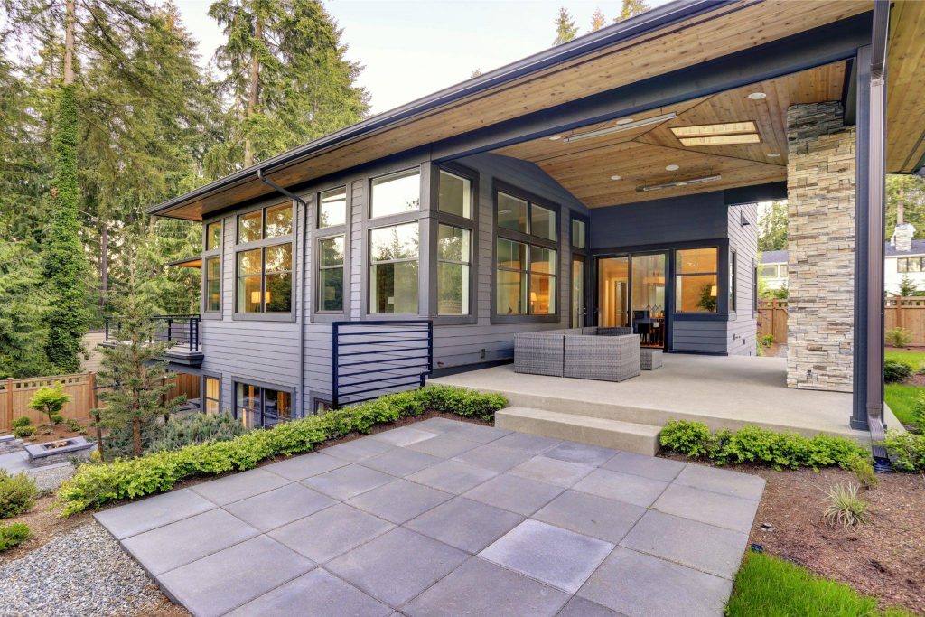 New modern home features a backyard with covered patio accented with stone fireplace