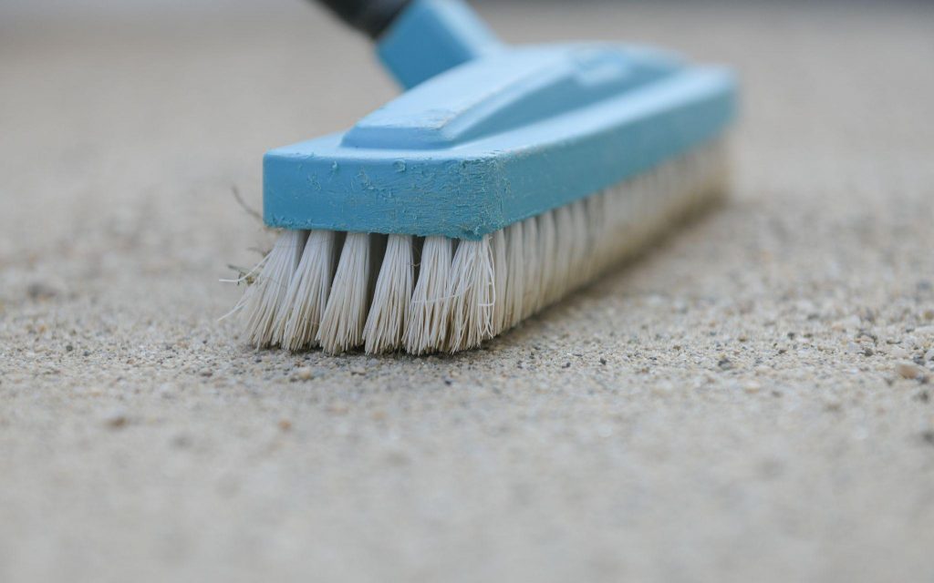 Cleaning the pavers from sand after creating a space in the backyard.