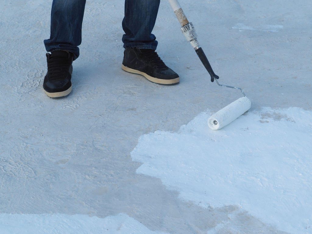 Man applies waterproof and thermal insulation of a roof from rain and sun.