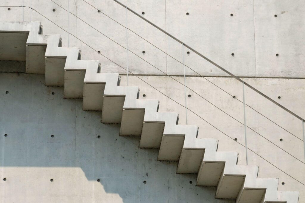 Cement stairs in outside a high modern building with handrails and sunlight shadow.