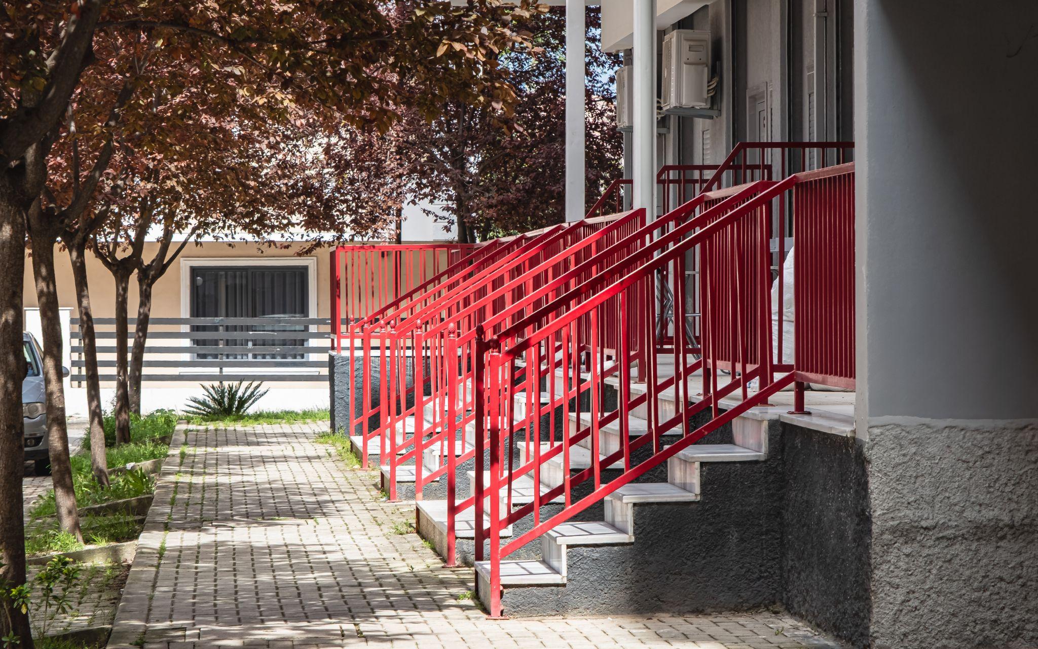 Steel handrail painted red color at stairways of a residential apartment building.